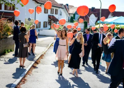Hochzeitsgaeste mit roten Luftballons bei einer Hochzeitsfotografie in Gilching nahe Muenchen, Gasthof Widmann.
