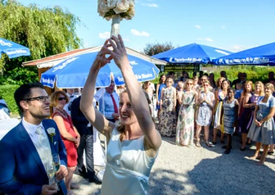 Braut wirft Blumenstrauss bei Hochzeitsfeier in Gasthof zur Post, Freudenlachen der Gaeste, Hochzeitsreportage.