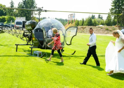Brautpaar in Neukeferloh bei einer Hochzeit, spaziert über einen Rasen zu einem Hubschrauber. Hochzeitsreportage.