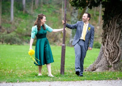 Brautpaar lachend im Kurpark Bad Tölz. Hochzeitsreportage mit Brautstrauss und Anzug bei Baum.