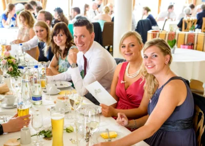 Gaste bei einer Hochzeit in Oberbayern, fröhliche Feier in der Hochzeitsfotografie, festlicher Tisch mit Dekoration.