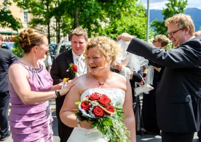 Brautpaar bei der Hochzeit in Bayern, Braut mit Blumenstrauss lacht, festgehalten von Hochzeitsfotograf.