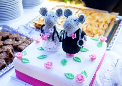 Hochzeitskuchen mit gestrickten Mauspaar-Figuren im Gasthof zur Post, dekoriert mit rosa Blumen.