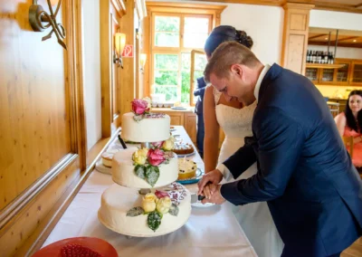 Brautpaar schneidet Hochzeitstorte bei Feier im Gasthof Widmann, nahe München. Hochzeitsfoto von unvergesslichem Moment.