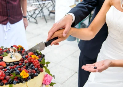 Brautpaar schneidet Hochzeitstorte mit Beeren bei Schliersberg-Alm, Hochzeitsfotograf dokumentiert diesen besonderen Moment.