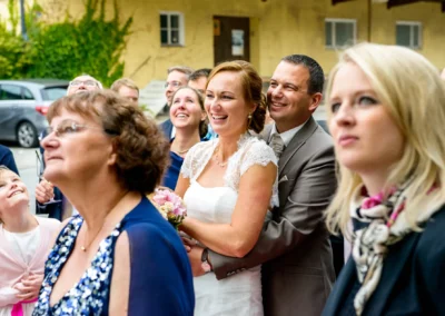 Hochzeitsfoto in Neufarn bei München: Brautpaar und Gaeste lachen bei Feier im Freien, gehalten in Gasthof Stangl.