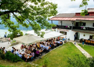 Hochzeitsgesellschaft beim Empfang auf Schliersberg-Alm mit traumhaftem Blick auf den Schliersee in Oberbayern.