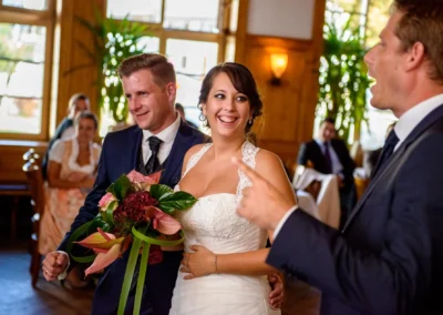 Brautpaar und Gaeste lachen bei der Hochzeitsfeier im Gasthof Widmann. Hochzeit in Gilching festgehalten.
