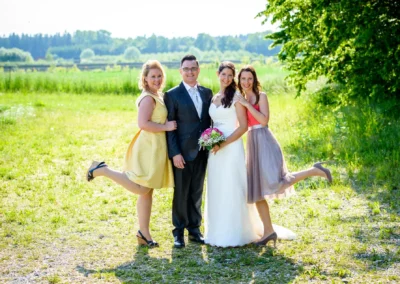 Brautpaar mit zwei Frauen im Garten von Schloss Sulzemoos bei der Hochzeit, alle lachen in die Kamera.