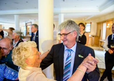 Tanzendes Paar bei einer Hochzeit in Oberbayern, eingefangen vom Hochzeitsfotografen. Fröhliche Gäste im Hintergrund.