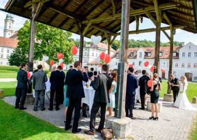 Hochzeitsgesellschaft mit Luftballons feiert im Freien nahe Kloster Furstenfeld, Hochzeitsfotograf begleitet das Event.
