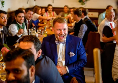 Lachender Gast während Hochzeitsfeier im Gasthof Widmann nahe München. Hochzeitsfotografie mit fröhlicher Stimmung.