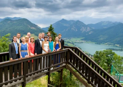 Gruppe bei Hochzeit auf Schliersberg-Alm mit Blick auf Berge und See, festgehalten von Hochzeitsfotograf in Oberbayern.