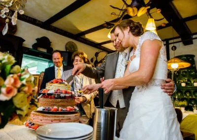 Brautpaar schneidet Hochzeitstorte bei Feier im Gasthof Stangl, festgehalten in Hochzeitsreportage.