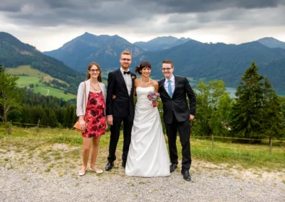 Brautpaar mit Freunden vor Bergkulisse, Hochzeitsfoto in Oberbayern, aufgenommen bei einer Hochzeit.