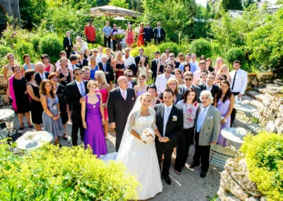 Hochzeitsgesellschaft in der Alten Gaertnerei Taufkirchen bei sonnigem Wetter, festlich gekleidet, Gruppenfoto.