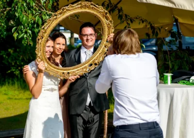 Brautpaar posiert mit einem goldenen Rahmen bei einer Hochzeit auf Gut Schloss Sulzemoos. Hochzeitsfotograf fotografiert.