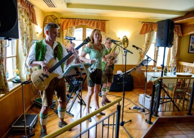 Musikband spielt bei Hochzeitsfeier in traditioneller Kleidung, aufgenommen von Hochzeitsfotograf in Holzkirchen.