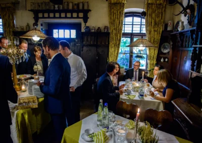 Gäste bei der Hochzeitsfeier im Gasthof Stangl, genussvoll speisend und plaudernd in festlicher Stimmung.
