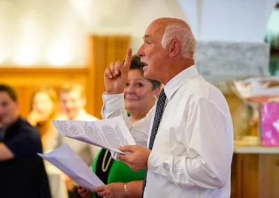 Mann mit Redenotizen bei Hochzeit auf Gut Schloss Sulzemoos, umgeben von aufmerksam zuhörenden Gästen.