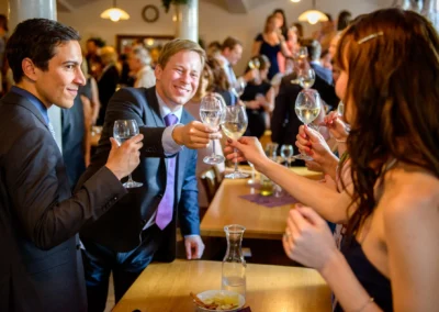 Gaste stoßen mit Weingläsern bei einer Hochzeit im Gasthof Widmann an. Hochzeitsfotografie nahe München.
