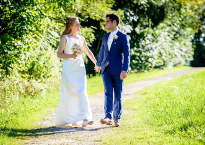 Brautpaar bei Hochzeit in Assenhausen, spazierend auf Waldweg, festgehalten in Hochzeitsportraits im Sonnenlicht.