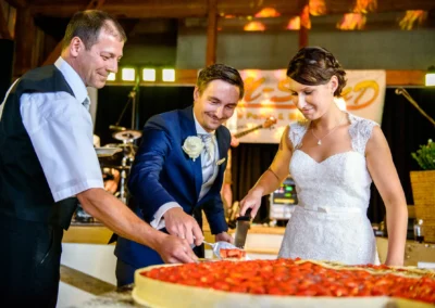 Brautpaar schneidet Hochzeitstorte im Eventstadl zur Alten Sage, festgehalten von Hochzeitsfotograf in Oberbayern.