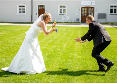 Brautpaar spielt mit Seifenblasen im Garten, aufgenommen bei einer Hochzeit im Brucker Land, nahe Muenchen.