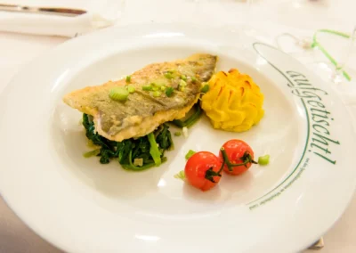 Hochzeitsfoto bei Gut Schloss Sulzemoos: Teller mit Fisch, Kartoffelpuree, Blattgemuese und Kirschtomaten.