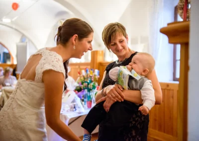 Braut lacht mit Gast und Baby bei Hochzeit auf Gut Schloss Sulzemoos; herzliche Hochzeitsreportage-Momente.
