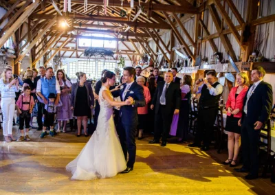 Brautpaar beim Hochzeitstanz umgeben von Gaesten in einem rustikalen Saal in Moosach bei Grafing. Hochzeitsfoto.