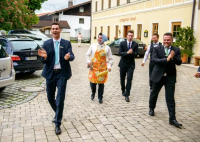 Männer in Anzügen klatschen bei Hochzeitsfeier im Freien vor Landgasthof Altwirt. Hochzeitsfotografie Nähe München.