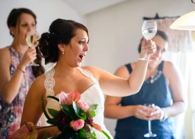 Braut hebt Glas bei Hochzeitsfeier im Gasthof Widmann, fröhlicher Moment zwischen Freunden in der Hochzeitsfotografie.