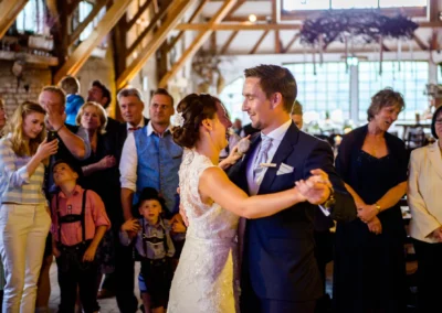 Brautpaar tanzt bei Hochzeit im Eventstadl zur Alten Saege, umgeben von Gaesten. Hochzeitsfotografie in Oberbayern.