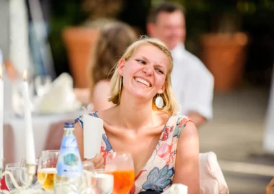 Lächelnde Frau bei einer Hochzeit in Taufkirchen bei München, umgeben von Kerzen und Getränken. Hochzeitsreportage.