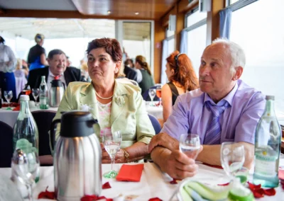 Gäste bei einer Hochzeit in Bayern sitzen an einem gedeckten Tisch, umgeben von Getränken und Dekorationen.