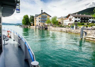 Blick vom Boot auf die Uferpromenade bei einer Hochzeit am Tegernsee, Bayern. Hochzeitsfotografie in malerischer Umgebung.