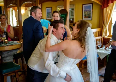 Brautpaar tanzt ausgelassen bei Hochzeit in Oberbayern, umgeben von Gaesten. Hochzeitsfotografie in froehlicher Stimmung.