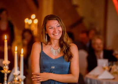 Lachende Frau bei Hochzeit in Gut Georgenberg, Kerzenlicht im Hintergrund, Hochzeitsfotograf aus Oberbayern erstellt.