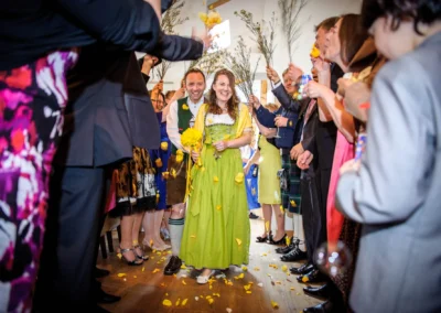 Brautpaar laeuft durch Spalier von Gaesten mit Blütenblaettern, aufgenommen bei einer Hochzeit im Bio Landhotel Moarwirt.