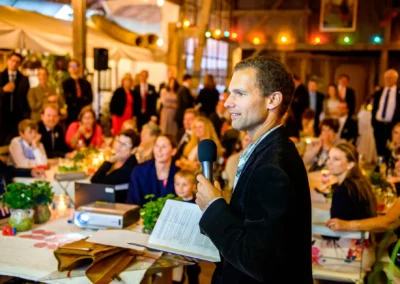 Mann haelt Rede bei Hochzeit im Gasthof Stangl, Gaeste lauschen gespannt. Hochzeitsfoto aus Neufarn bei Muenchen.