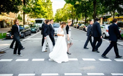 Hochzeitsgesellschaft ueberquert Strasse bei Hochzeit in Muenchen, festgehalten von Hochzeitsfotograf für Reportage.