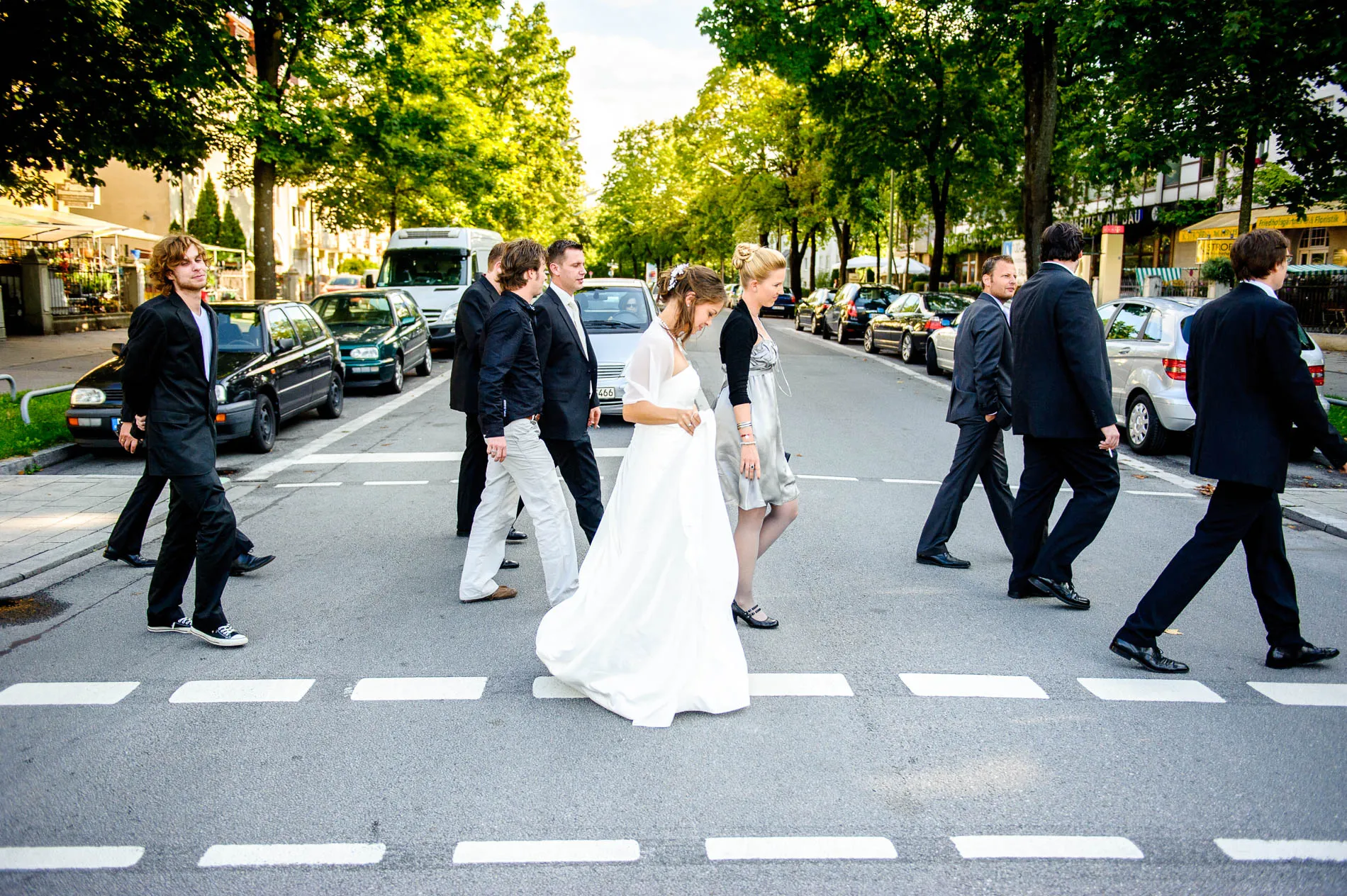 Hochzeitsgesellschaft ueberquert Strasse bei Hochzeit in Muenchen, festgehalten von Hochzeitsfotograf für Reportage.