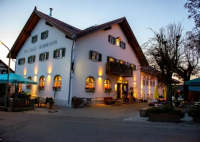 Abendaufnahme des festlich beleuchteten Gasthof Widmann, Gilching, bei einer Hochzeitsfeier. Hochzeitsfotografie.