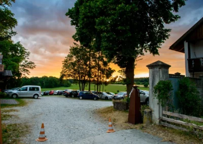 Autos parken bei Sonnenuntergang beim Gut Georgenberg. Hochzeitsfotografie in Oberbayern auf Schotterplatz.