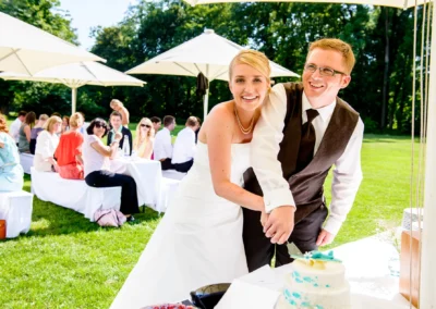 Brautpaar schneidet Hochzeitstorte im Freien in Oberbayern, aufgenommen bei einer Hochzeitsreportage.
