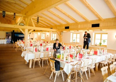 Hochzeitsfeier in Kreuth, festlich gedeckte Tische in einem rustikalen Saal, Hochzeitsfotografie in Bayern.