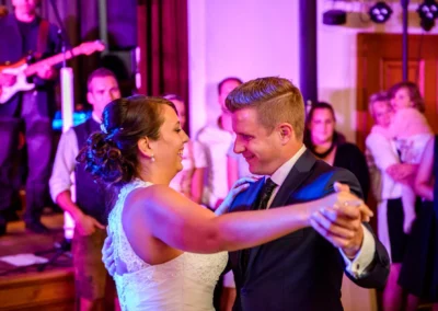 Braut und Bräutigam tanzen auf Hochzeit im Gasthof Widmann, mit Gästen im Hintergrund. Hochzeitsfotografie in München.