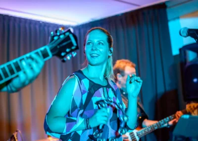 Eine Band spielt bei einer Hochzeit im Gasthof Widmann, mit einer Frau im Vordergrund, die ein Tamburin hält.