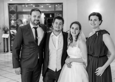 Vier Personen posieren lächelnd bei einer Hochzeit in Grosshartpenning, elegant gekleidet. Hochzeitsfotograf.